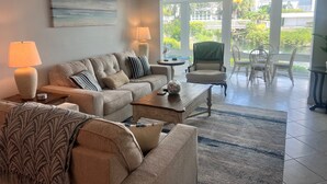 A living room with a sofa, armchairs, a coffee table, and a dining area with chairs and a table.