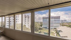 Una habitación con amplios ventanales, una silla y vistas a un edificio moderno y zonas verdes.