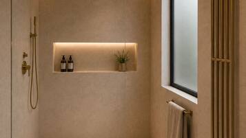 Un baño moderno con cabina de ducha de vidrio, un estante empotrado con artículos de aseo, un perchero y una ventana.