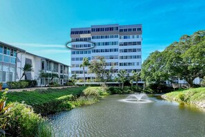 A modern building with a central courtyard featuring a water fountain, surrounded by greenery and palm trees.