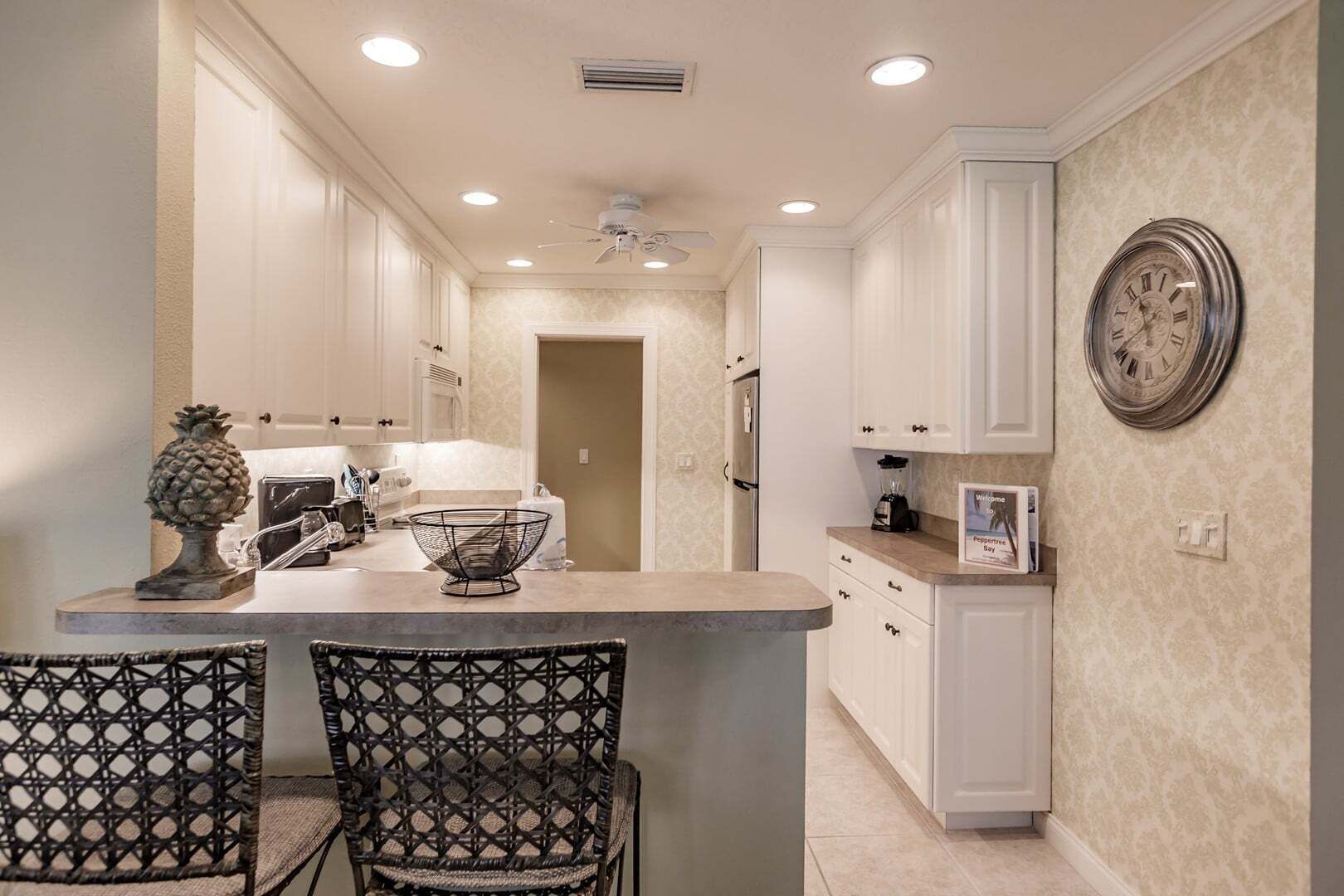 A kitchen with white cabinetry, a central island, and a decorative pineapple.