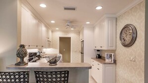 A kitchen with white cabinetry, a central island, and a decorative pineapple.