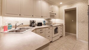 A kitchen with a stainless steel sink, a coffee maker, a toaster, and a microwave. - 1077 PD - Standard - Large Garden Oasis Condo (Siesta Key)