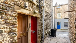 A narrow alleyway with stone walls, a red door, and a blue door in the background. - Sedbergh Penthouse - Kingbed - Tv - Wifi (Sedbergh)