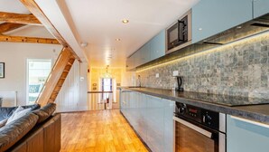 A modern kitchen with wooden beams, a herringbone floor, and a stone backsplash. - Sedbergh Penthouse - Kingbed - Tv - Wifi (Sedbergh)