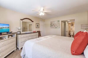 A hotel room with a bed, a dresser, a television, a ceiling fan, and a bathroom visible through an open door. - 1081 PD - Standard Plus - Unwind in Our Spacious Townhome Oasis (Siesta Key)