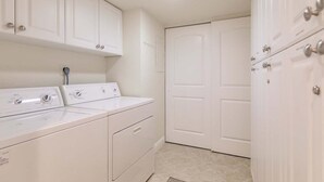 A laundry room with a washer and dryer, cabinets, and a door.