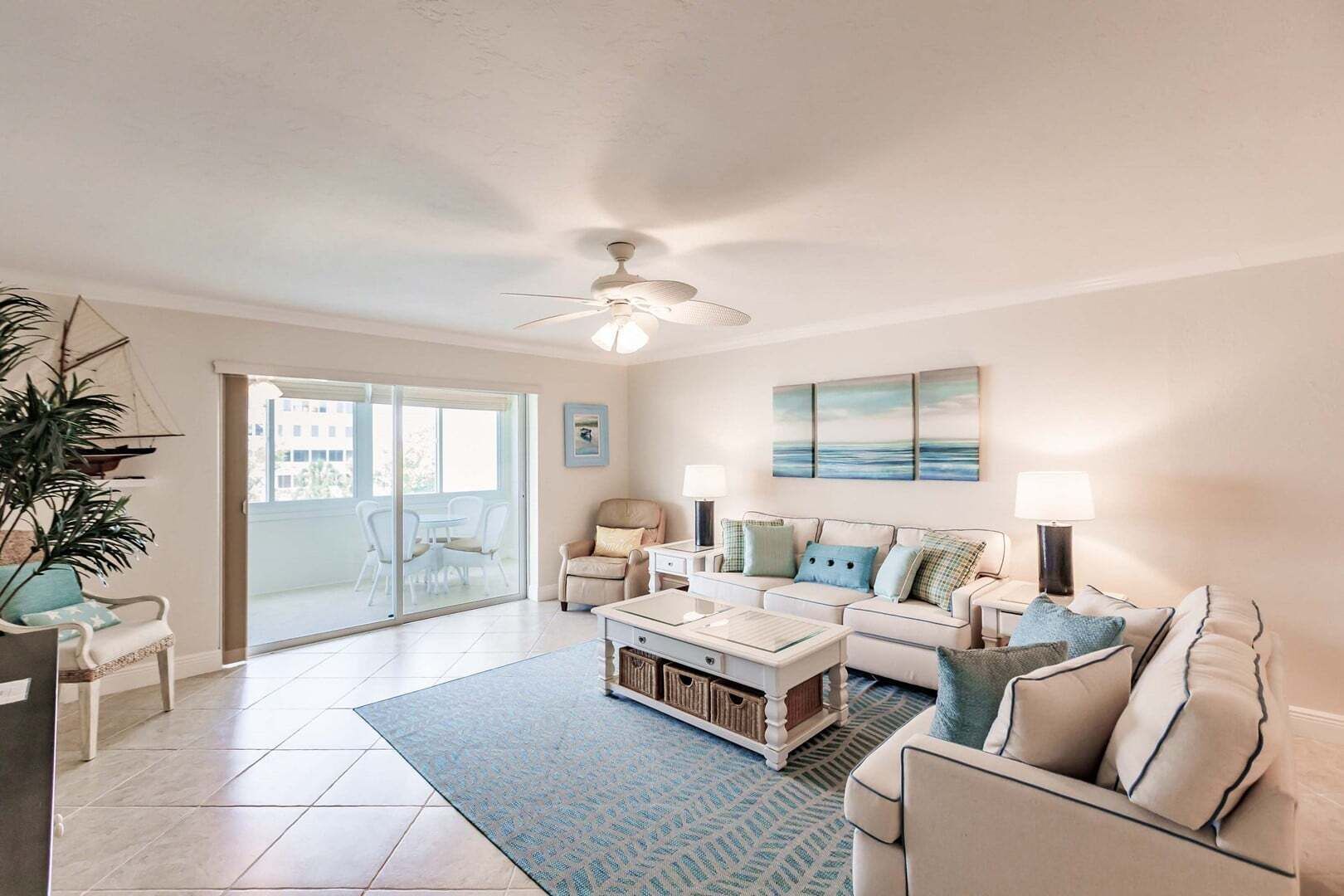 A living room with a ceiling fan, a sofa set, a coffee table, and a view through a glass door.