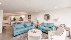A modern living room with two sofas, a coffee table, and a dining area in the background. - 1125-407 - Premium Plus - Step into Coastal Paradise (Siesta Key)