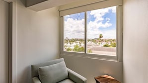 A corner room with a window overlooking a cityscape, a grey armchair, and a small wooden table. - 1125-407 - Premium Plus - Step into Coastal Paradise (Siesta Key)