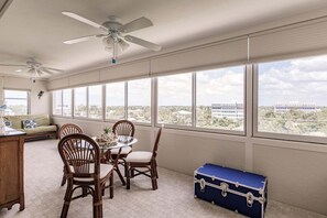 A room with a dining table, chairs, a blue suitcase, and a ceiling fan.