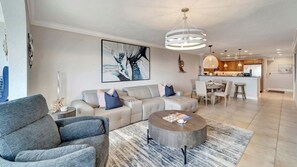 Ein modernes Wohnzimmer mit einem Ecksofa, einem runden Couchtisch und einem großen abstrakten Gemälde.