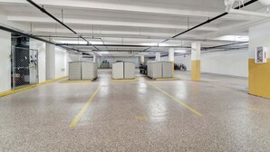 An indoor parking garage with concrete floors, yellow parking lines, and white pillars. - 1125-705 - Premium - Enjoy Seaside Splendor (Siesta Key)