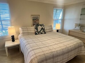 A bedroom with a bed, two bedside lamps, a nightstand, a dresser, and a framed picture on the wall.
