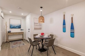 Een eethoek met een ronde tafel, vier stoelen, een hanglamp en twee aan de muur bevestigde paddleboards.