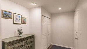Un couloir avec une commode en bois, des œuvres d’art encadrées et une série de portes blanches.