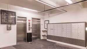 An elevator area with a directory sign, a set of lockers, and a control panel. - 1200-402 - Premium - Experience Serenity Steps from the Water (St. Petersburg)