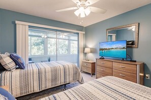 A bedroom with a bed, a dresser, a television, and a ceiling fan. - 1200-402 - Premium - Experience Serenity Steps from the Water (St. Petersburg)