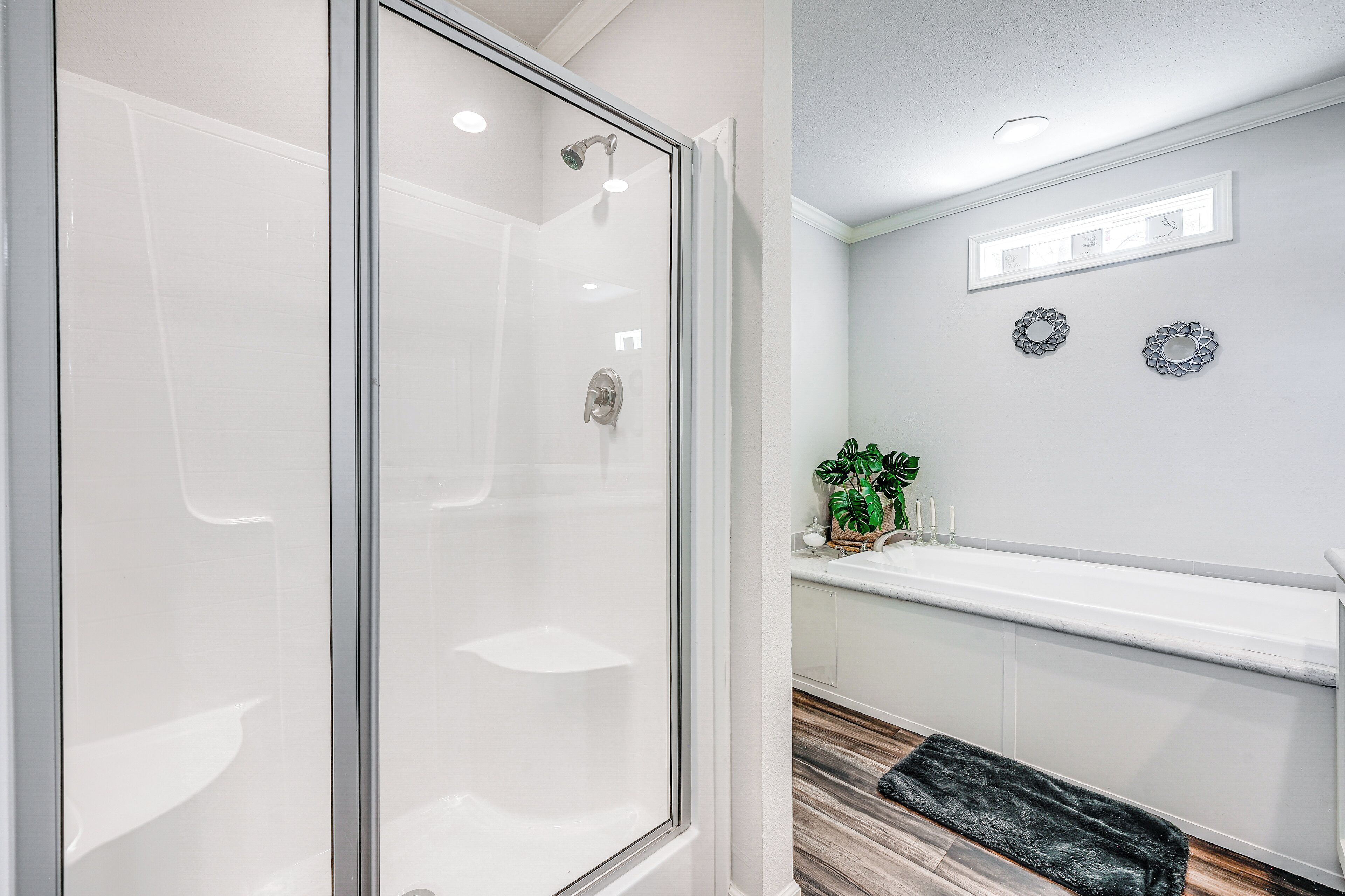 Une salle de bain moderne avec une douche à l’italienne en verre, une baignoire blanche et un plancher en bois.