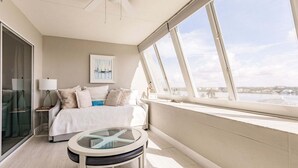 A bedroom with a bed, a glass table, a window with a view, and a ceiling fan. - 1200-602 - Premium Plus -Enjoy Relaxing Bayfront Bliss (St. Petersburg)