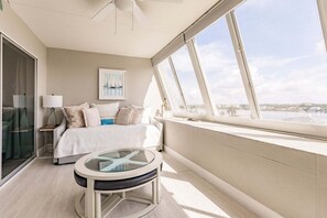 A bedroom with a bed, a glass table, a window with a view, and a ceiling fan. - 1200-602 - Premium Plus -Enjoy Relaxing Bayfront Bliss (St. Petersburg)