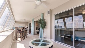A sunlit balcony with a dining table, chairs, and a potted plant. - 1200-602 - Premium Plus -Enjoy Relaxing Bayfront Bliss (St. Petersburg)
