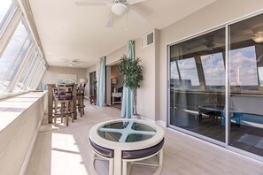 A sunlit balcony with a dining table, chairs, and a potted plant. - 1200-602 - Premium Plus -Enjoy Relaxing Bayfront Bliss (St. Petersburg)