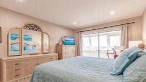 A bedroom with a bed, a dresser, a television, and a view of the outside. - 1200-602 - Premium Plus -Enjoy Relaxing Bayfront Bliss (St. Petersburg)