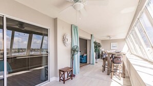 A spacious room with a large sliding glass door, a ceiling fan, a dining area with a table and chairs, and a view of the outdoors. - 1200-602 - Premium Plus -Enjoy Relaxing Bayfront Bliss (St. Petersburg)