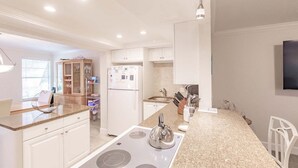 Een moderne keuken met witte kastjes, een ingebouwd fornuis en een aanrecht met een waterkoker.