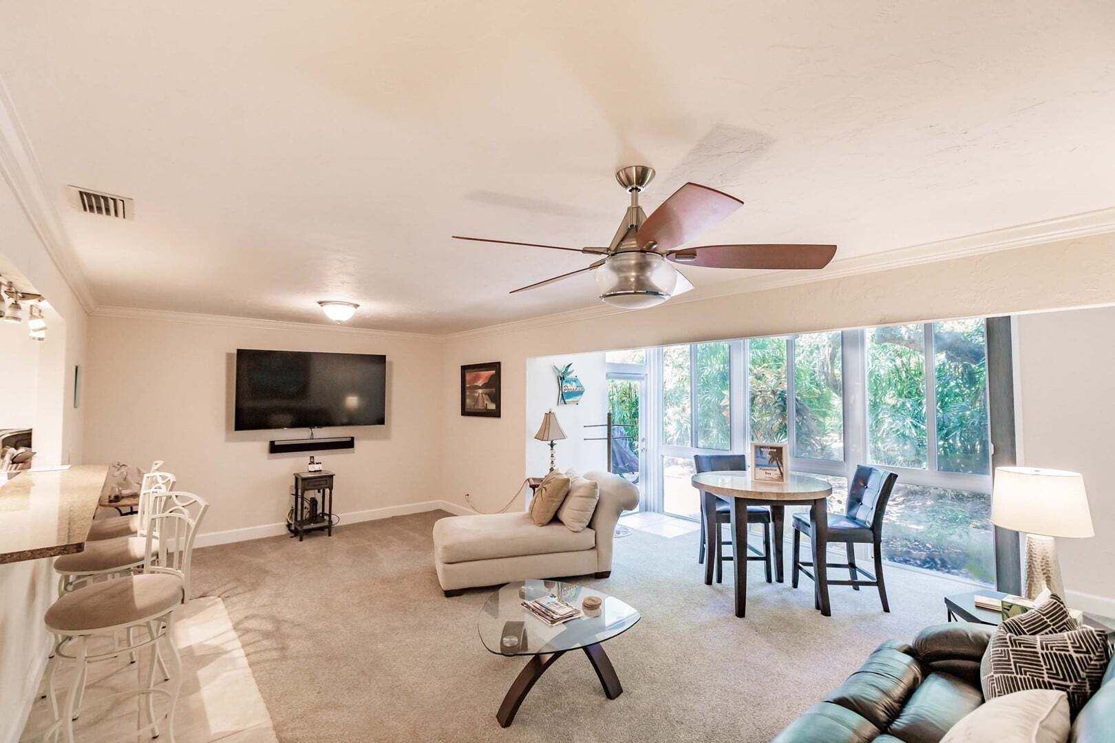 A living room with a sofa, a coffee table, a TV, and a dining area with chairs.