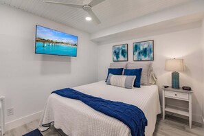 A bedroom with a bed, a nightstand, a lamp, and wall art.