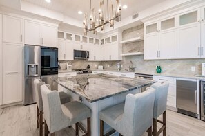 A modern kitchen with white cabinetry, a marble island, and stainless steel appliances.
