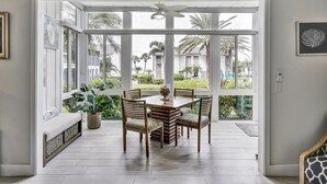 Een ruime kamer met een grote schuifdeur naar een balkon met uitzicht op palmbomen en een gebouw.