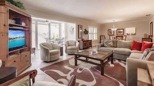 A spacious living room with a television, two armchairs, a sofa, and a coffee table.
