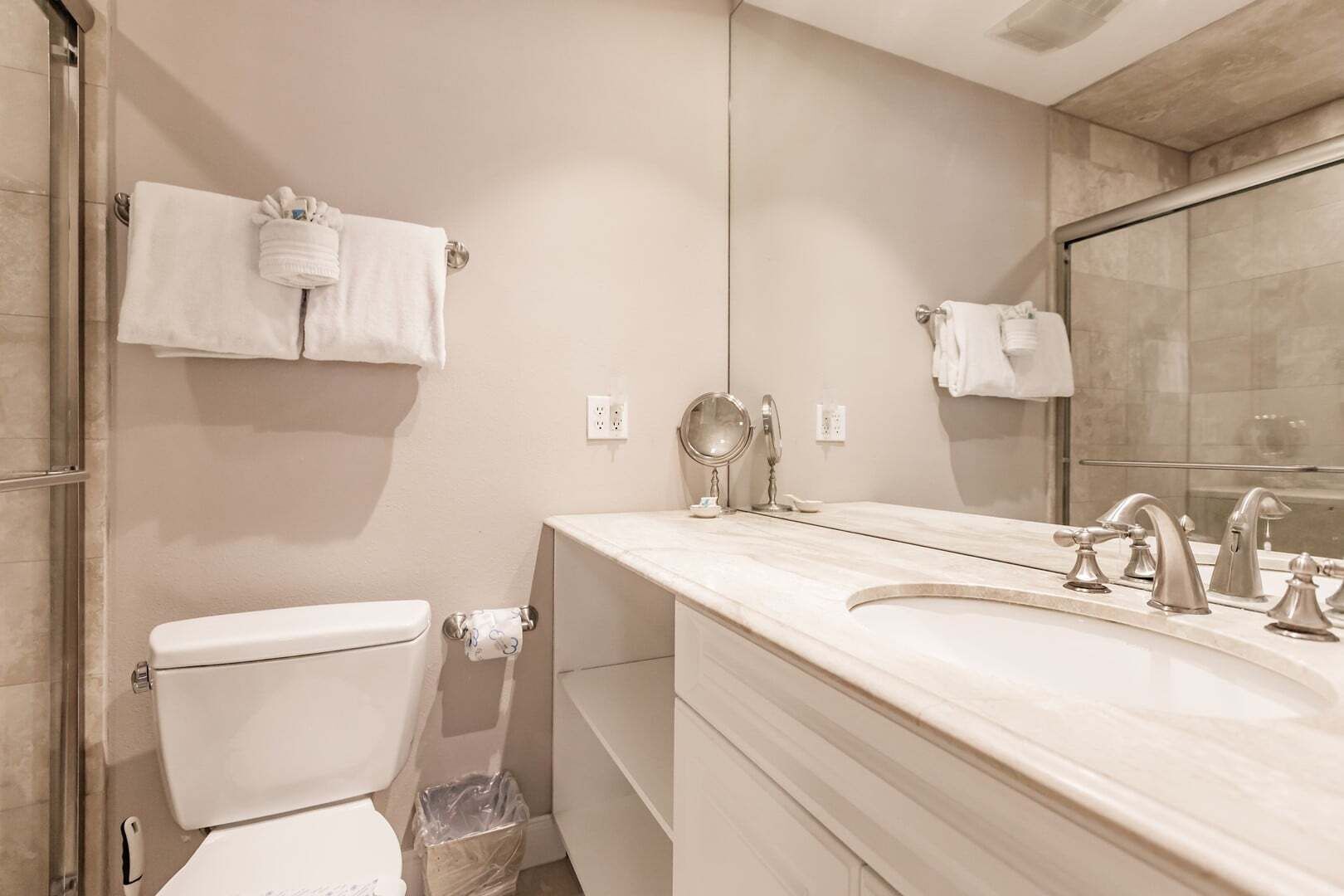 Een badkamer met toilet, wastafel met spiegel en douche.