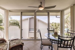 A sunlit patio with a glass table, chairs, and a ceiling fan. - 6052 WPW - Standard Plus - Spacious with a fabulous Bay View (Sarasota)