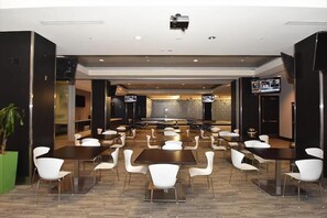 Conference room with a central stage, rows of seating, and large screens on either side.