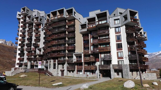 A multi-story hotel with balconies, a stone facade, and a mountainous backdrop. - 300m from ski slopes, 3rd floor, balcony, tv, ski locker, 52m², Tignes (Tignes)