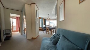 A living room with a blue sofa, a dining area with a table and chairs, and a kitchen in the background. - 300m from ski slopes, 3rd floor, balcony, tv, ski locker, 52m², Tignes (Tignes)