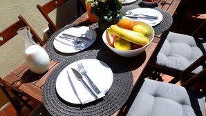 Ein gedeckter Tisch mit Tellern, Besteck, einer Obstschale und einem Blumenstrauß.