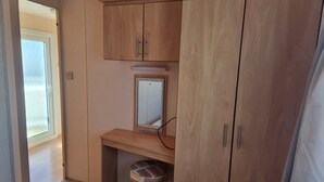 A bedroom with wooden cabinets, a small desk, a chair, and a window. - Ingoldmells Coral Beach on Entrance (Skegness)