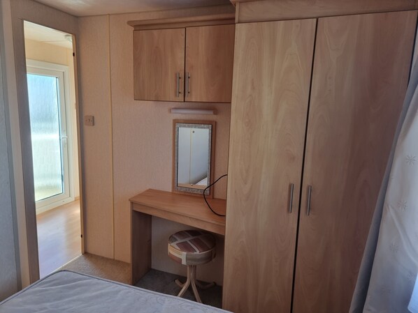 A bedroom with wooden cabinets, a small desk, a chair, and a window. - Ingoldmells Coral Beach on Entrance (Skegness)