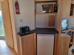 A compact kitchenette with a toaster, a small refrigerator, a microwave, and a television. - Ingoldmells Coral Beach on Entrance (Skegness)