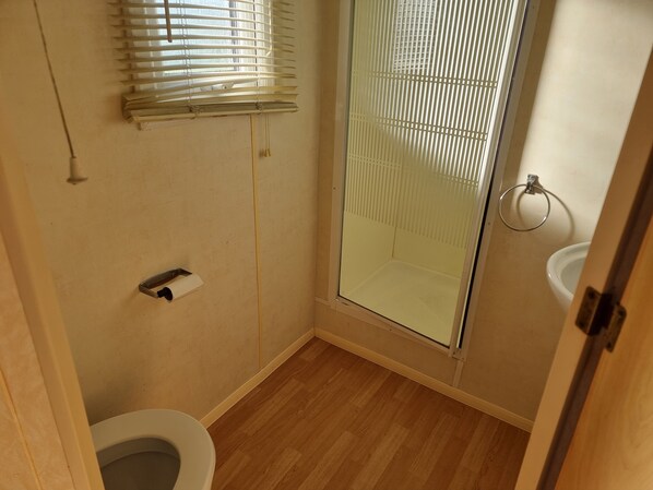 A small bathroom with a toilet, a glass shower enclosure, and a sink. - Ingoldmells Coral Beach on Entrance (Skegness)