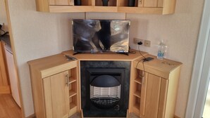 A compact living space with a TV, a small heater, and wooden cabinets. - Ingoldmells Coral Beach on Entrance (Skegness)