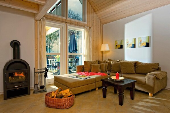 Una sala de estar acogedora con chimenea, un sofá, una mesa de centro y vistas al exterior.