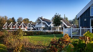 Uma fileira de casas modernas com guarda-corpos brancos e um gramado à frente.