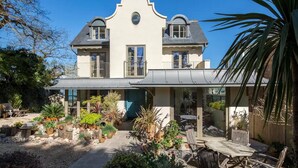 Une maison à deux étages dotée d’un patio couvert et d’un jardin.