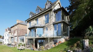 Une grande maison moderne, dotée de nombreuses fenêtres et d’une pelouse bien entretenue.